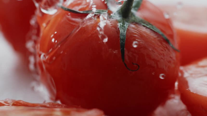 Water splashing onto tomato in slow motion