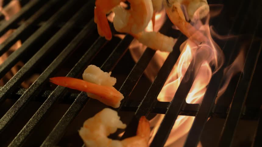 Shrimp fall onto a fiery grill