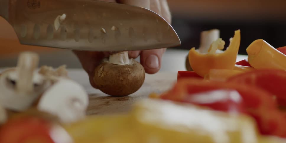 A person slices mushrooms in the kitchen
