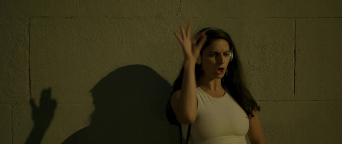 A woman dances outside in front of a wall