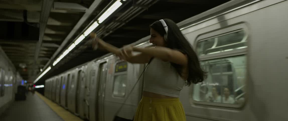 A woman dances playfully in a subway station
