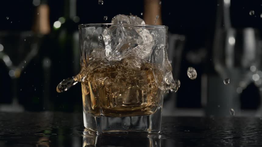 Liquid crashes into the ice filled glass