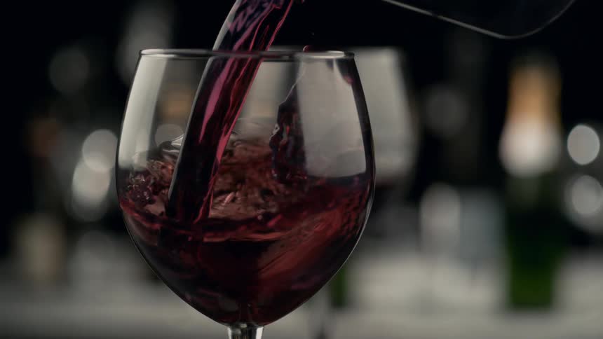 Red wine is poured into a wine glass