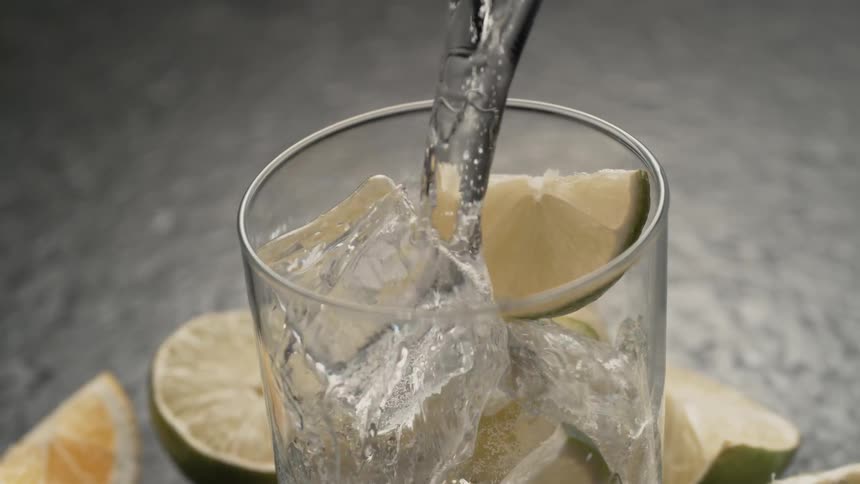 Beverage pouring over ice and limes