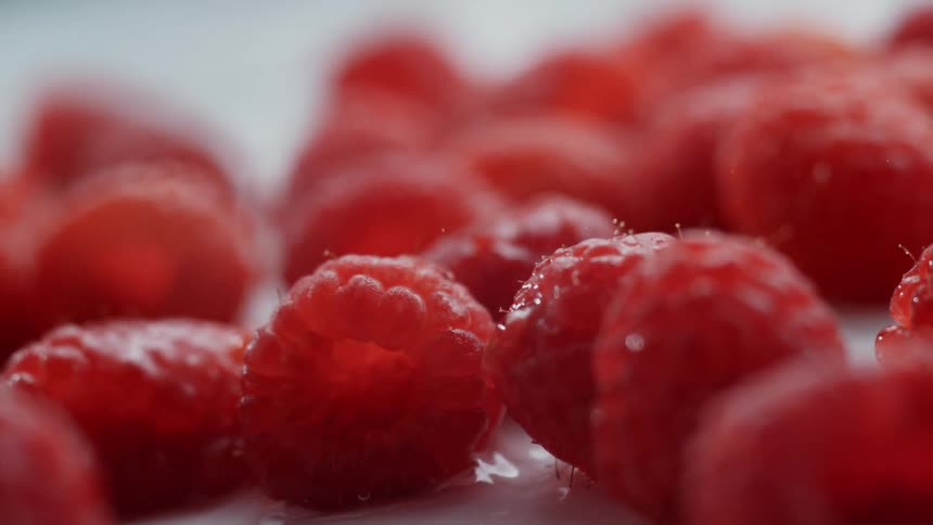 Raspberries and water falling on a table