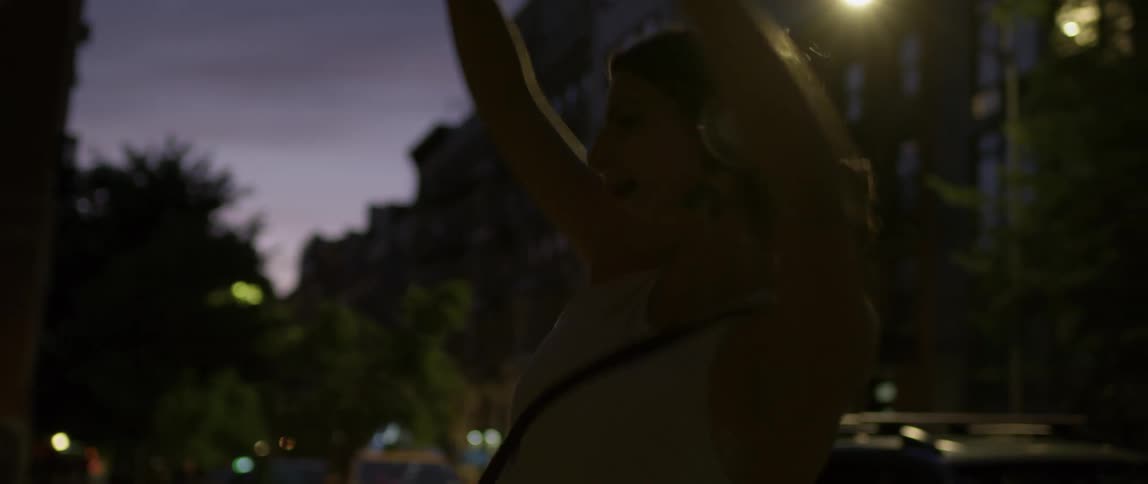 Woman listening to music and dancing in the street at night