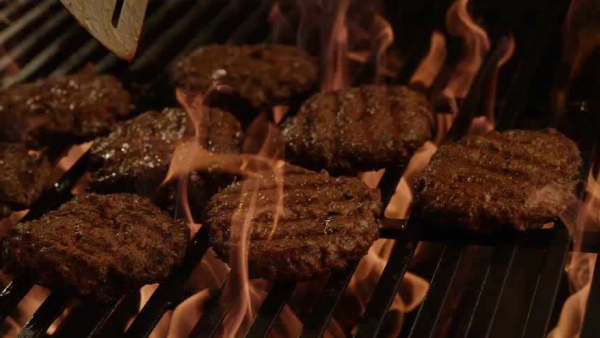 Burgers are flipped on the hot grill