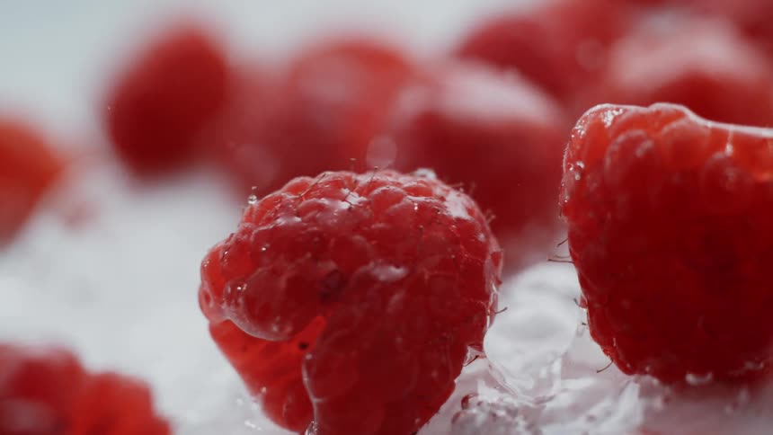 Water is splashed onto red raspberries