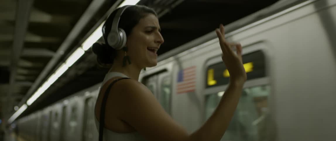 A woman dances in front of the moving train