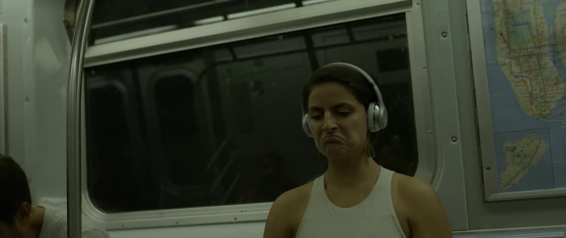 A woman is singing and dancing as she sits in a subway car