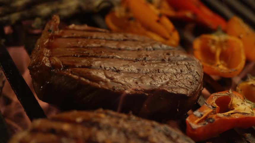 Steaks and peppers are being cooked on grill