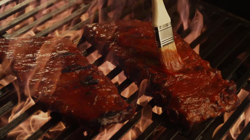 Ribs are basted as they cook on the grill