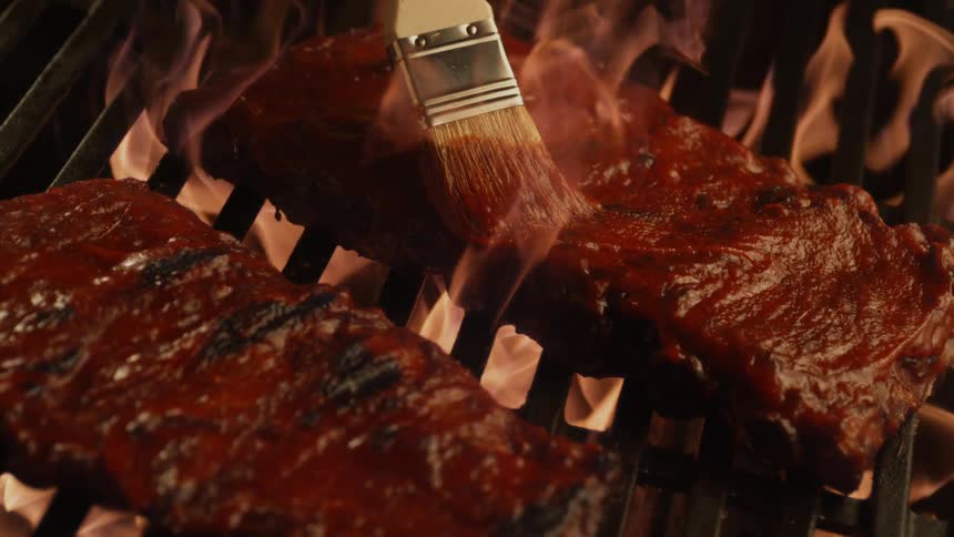 Ribs are basted as they cook on the grill