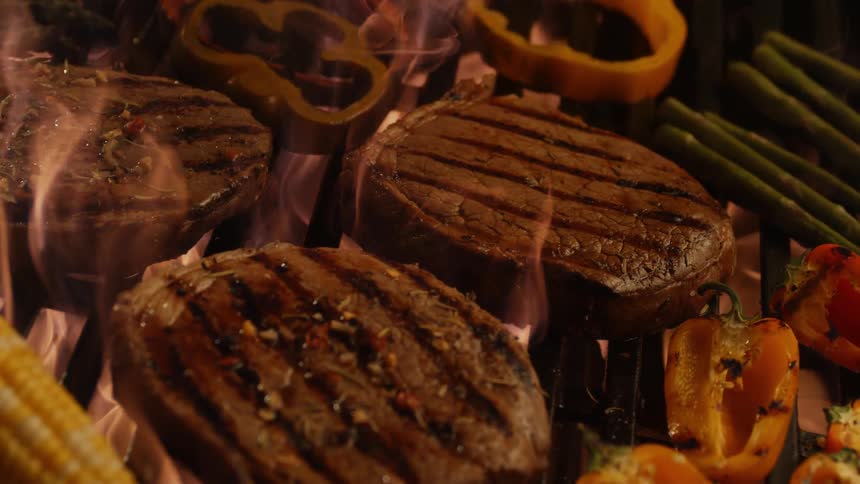 Steak and vegetables cook on a grill