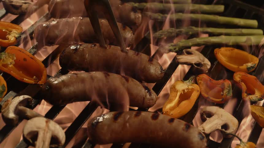 Sausages and vegetables are cooked on the grill