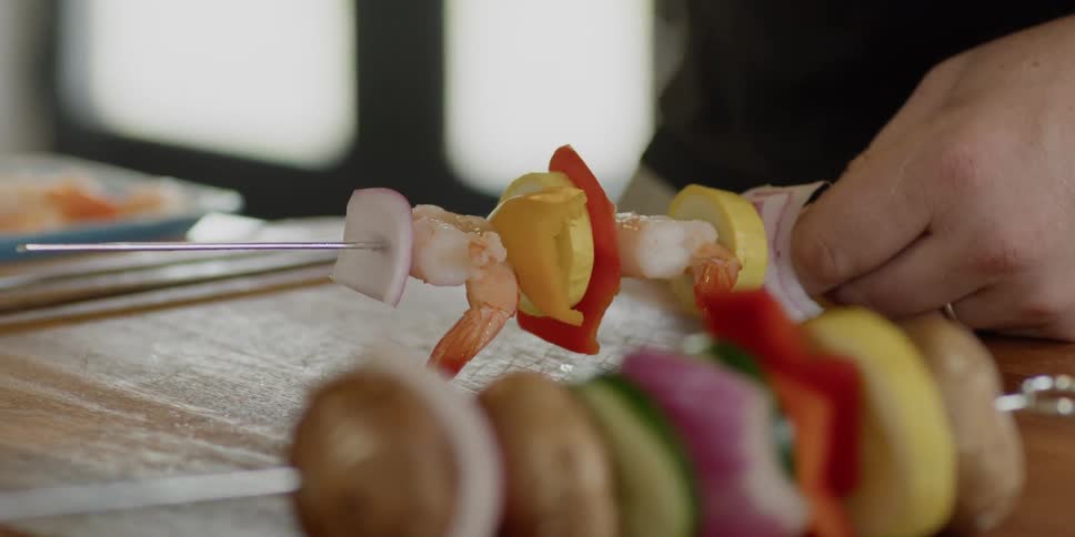 Meat and vegetables are put onto a skewer