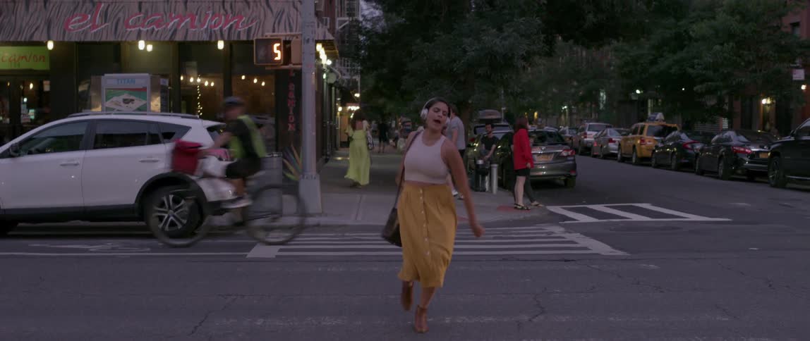 A woman dances as she crosses the street