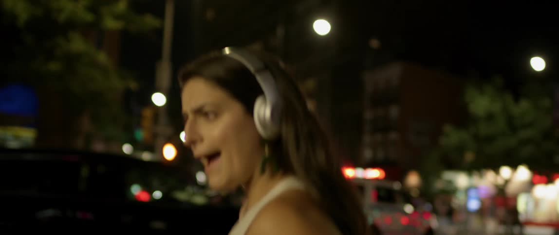 Woman listening to music and dancing in the street at night