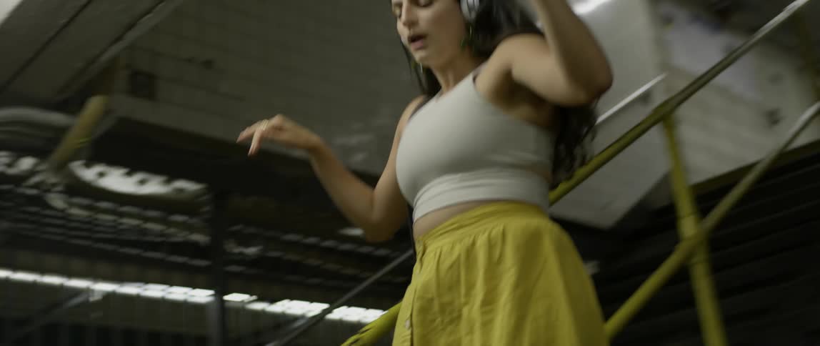 Woman wearing headphones sings as she descends the stairs