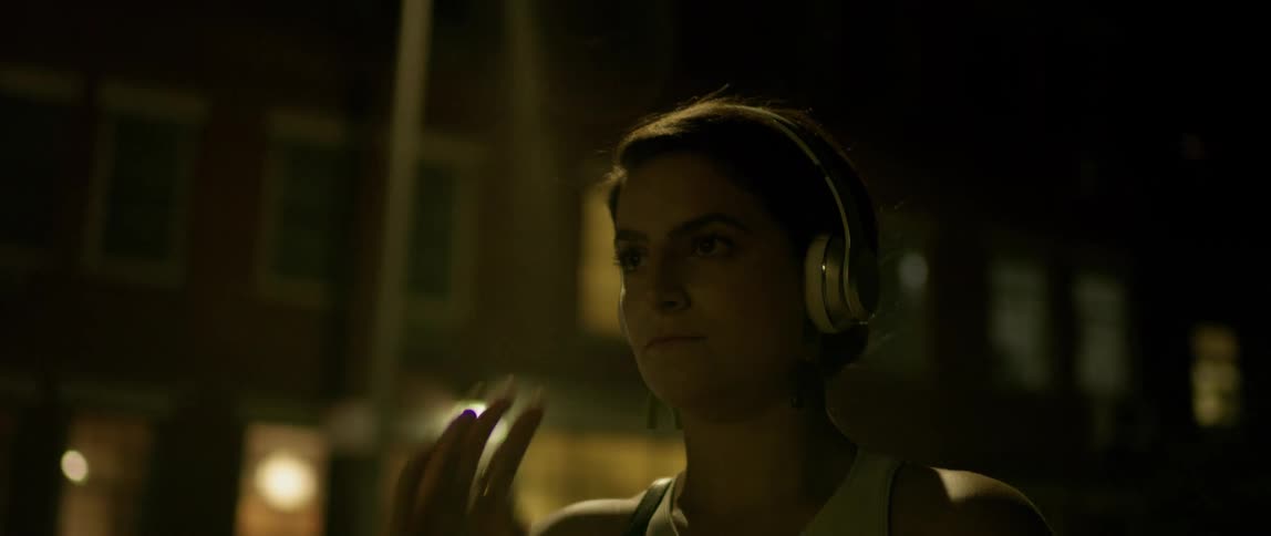 Woman wearing headphones standing in a city at night