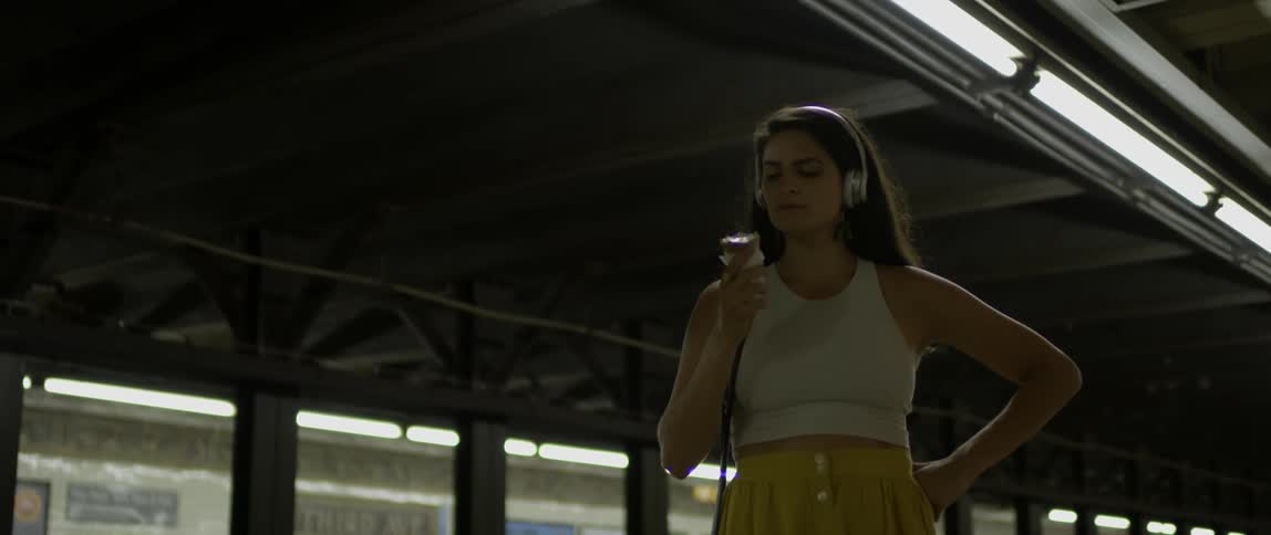 A woman eats an ice cream cone at a subway station