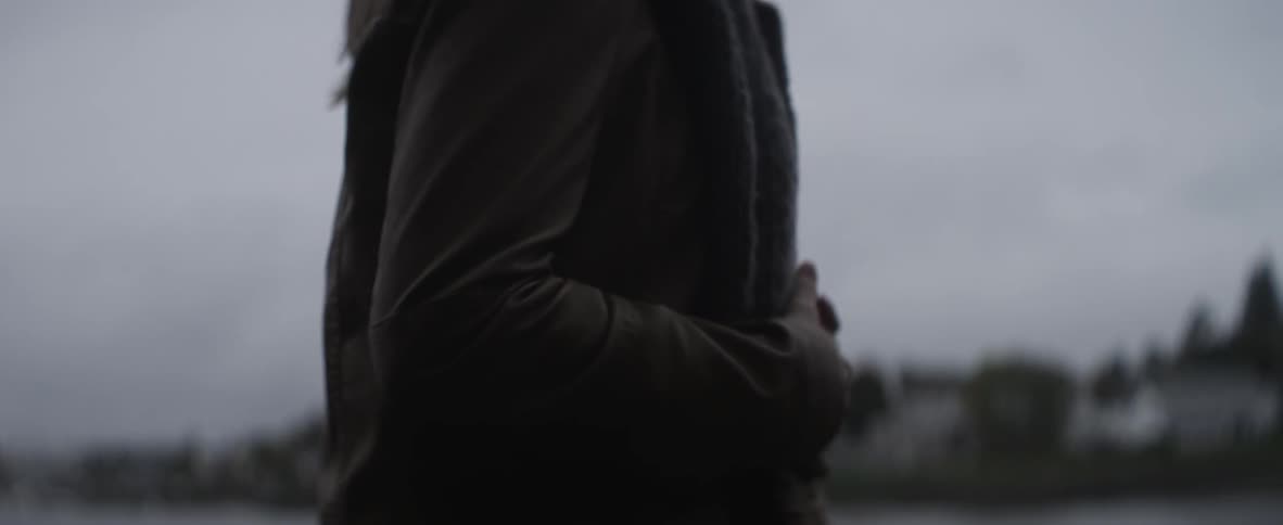 A woman in a coat walks and touches her coat