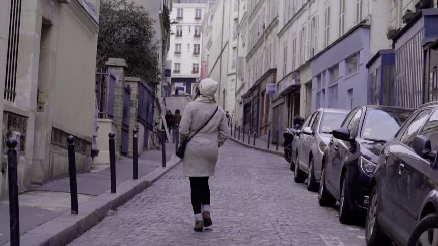 Woman walks down a narrow city street
