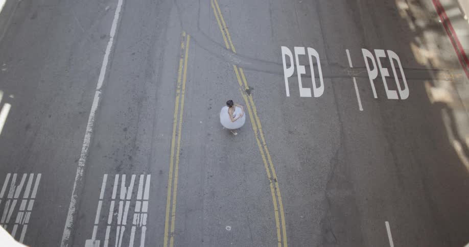 A ballerina is dancing in the middle of a street in daylight