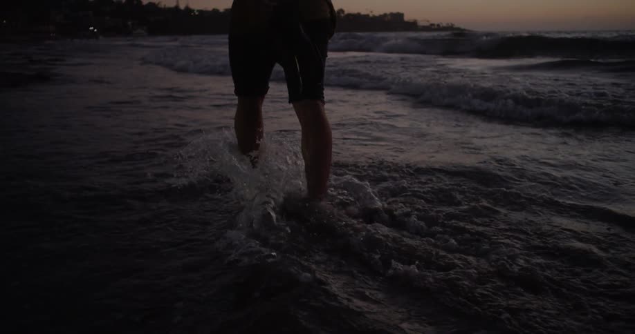 A man wades into the water on the beach