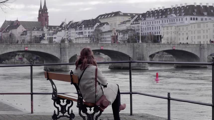 A woman sits down on the bench as people pass by
