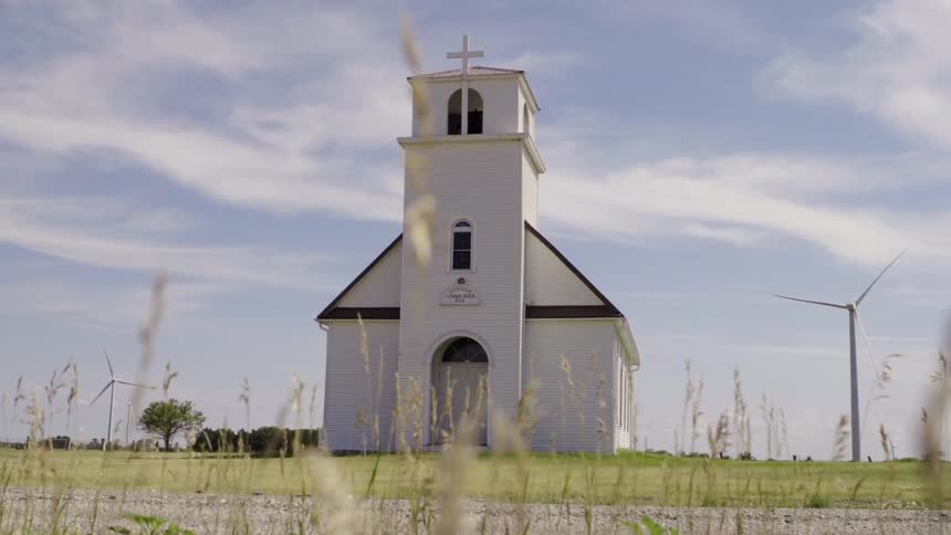Clouds hang above a small church in the field