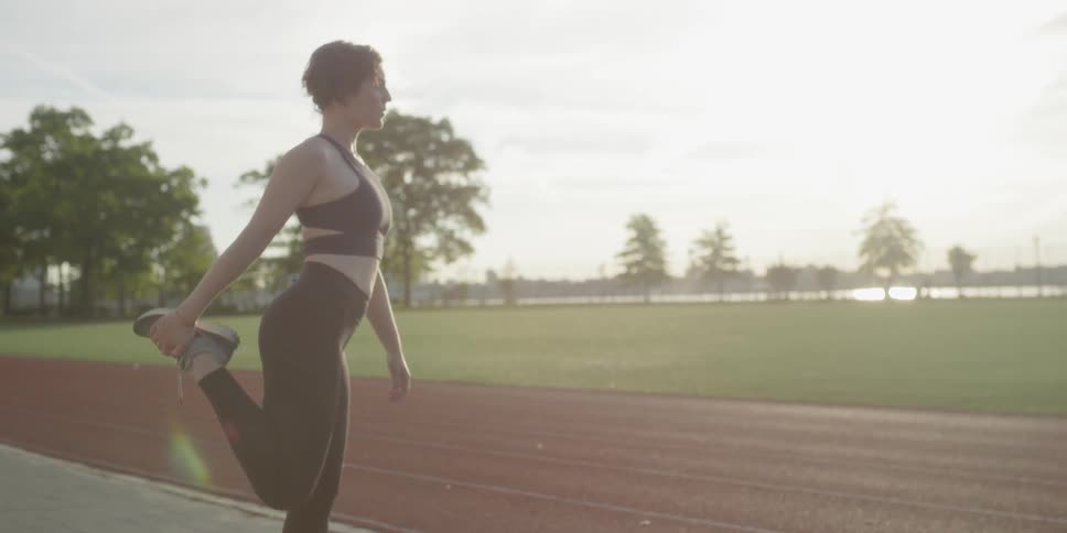 Woman stretching on a track in the afternoon