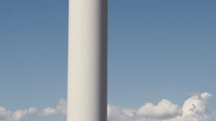 Windmills rotate in the field under blue skies