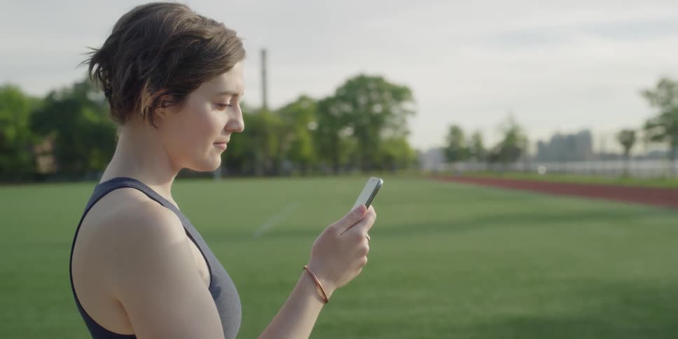 Woman looking at her phone on a field in the afternoon