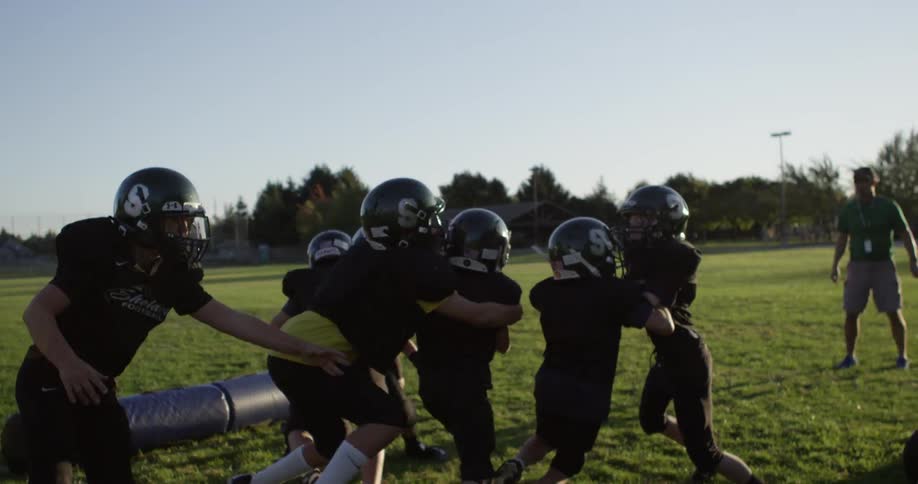 A football team practices on a grassy field
