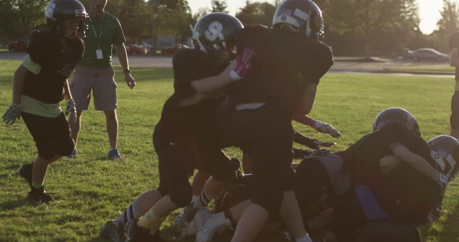 A youth football team practices in the daytime