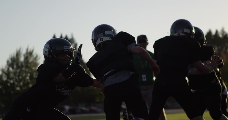 Football players practice on a grassy field