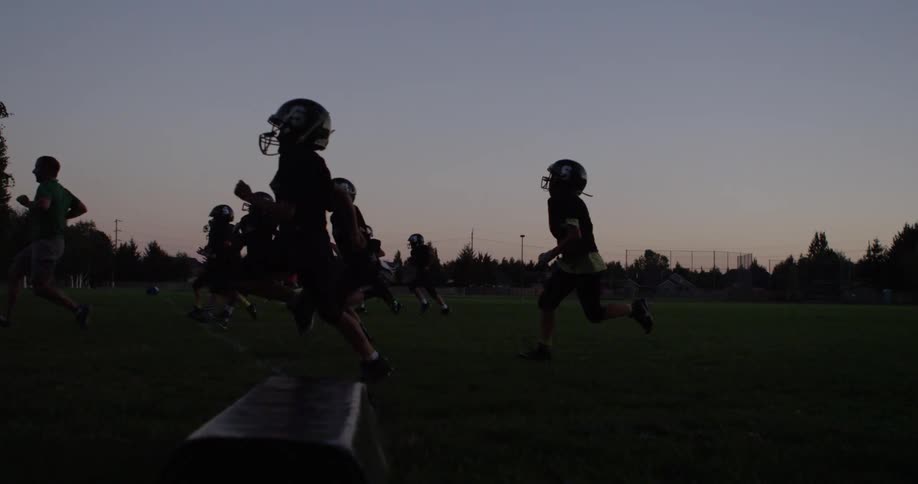 A youth football team practices in the evening