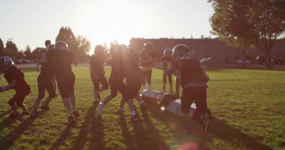 A youth football team practices in the daytime
