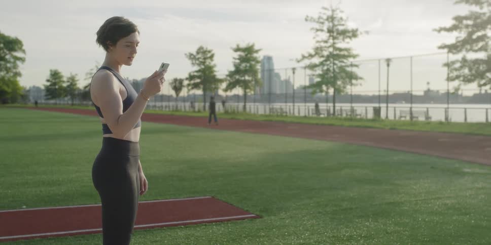 A woman looks at her phone by the jogging path
