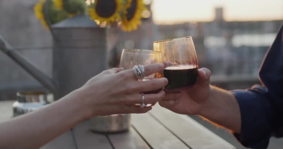 A woman and man toast with wine on the balcony