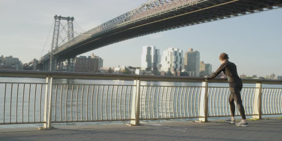 A woman jogger stretches against the railing