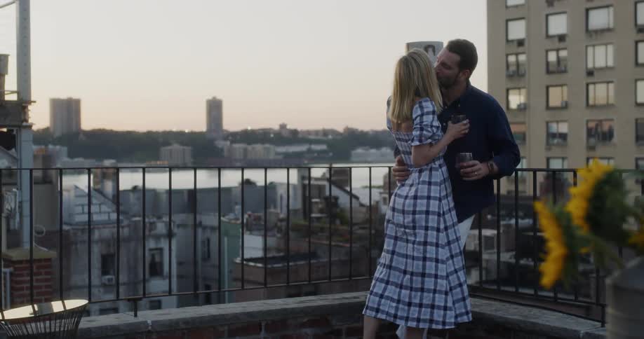 A man and woman kiss on the balcony