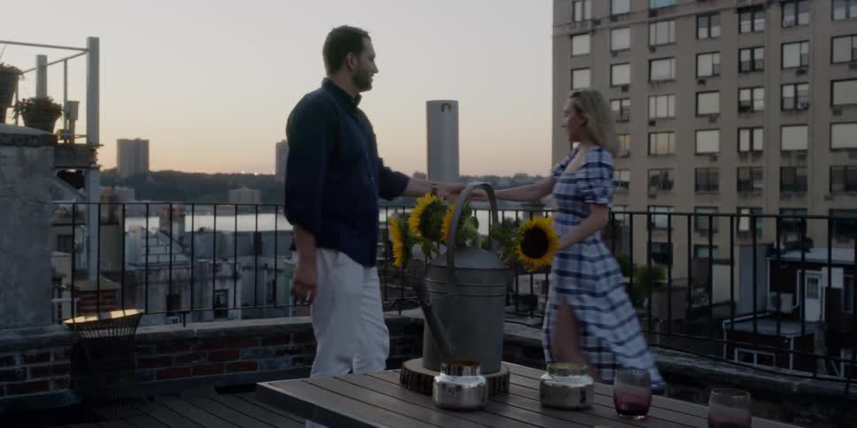 A couple are dancing on a balcony at sunset in an urban setting