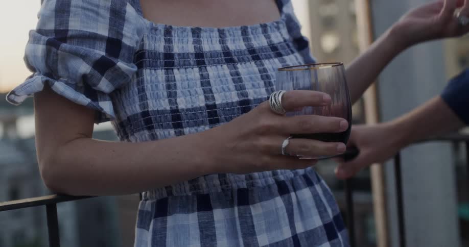 A woman holds a glass of red wine on the balcony