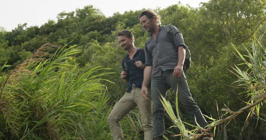 Two men stand on a hillside and look at the greenery