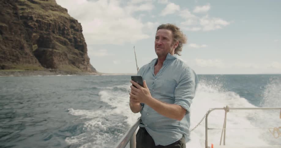 Man taking a selfie while on a boat near mountains