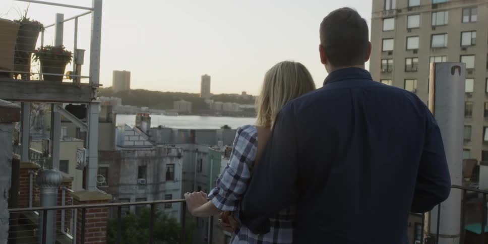 A man and woman enjoy the view on a building rooftop