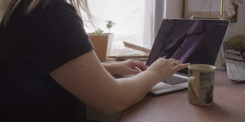 Woman sitting down typing on laptop during the afternoon