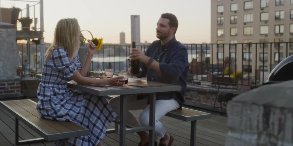 A man and woman drink wine on the balcony